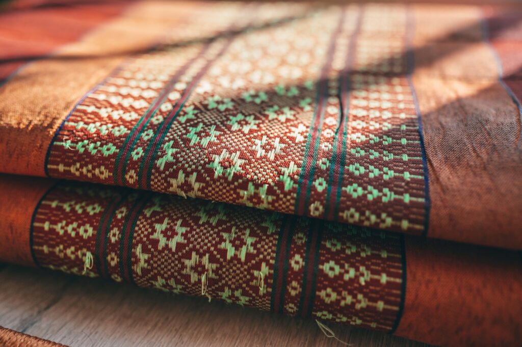 Foto de dois tecidos ornamentados e coloridos sobrepostos um sobre o outro