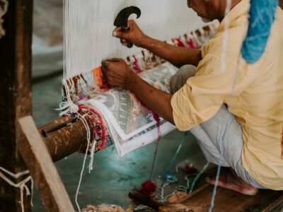 Imagem de um artesão indiano trançando um tapete em tear manual