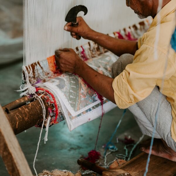 Imagem de um artesão indiano trançando um tapete em tear manual